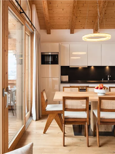 Ein modernes Esszimmer mit Holzofen und hellem Interieur. Große Fenster bieten einen schönen Blick auf die Umgebung.