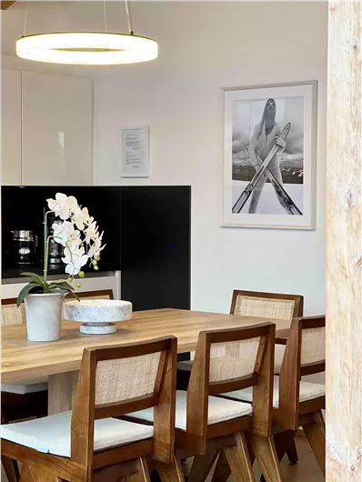 Ein eleganter Essbereich mit einem Holztisch und modernen Stühlen. An der Wand hängt ein schwarz-weißes Bild einer Skifahrerin.