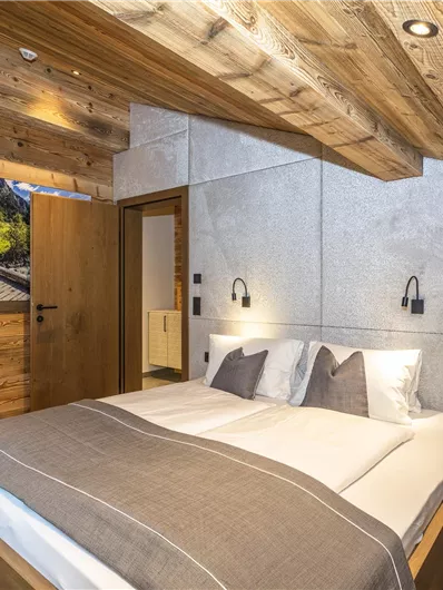 Een moderne slaapkamer met een houten plafond en een comfortabel tweepersoonsbed. Een warm ingerichte sfeer met zachte verlichtingsaccenten.