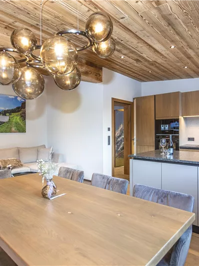 Een moderne woning met houten plafonds en elegante meubels. De eetruimte is stijlvol ingericht met een grote tafel en een open keuken.