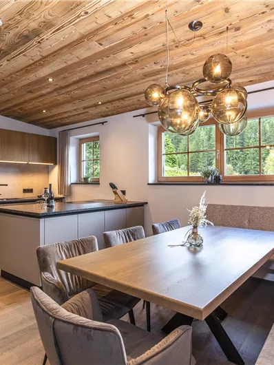 Een moderne keuken met houten plafonds en elegante meubels. Het eethoek is helder en vriendelijk, met een grote tafel en comfortabele stoelen.