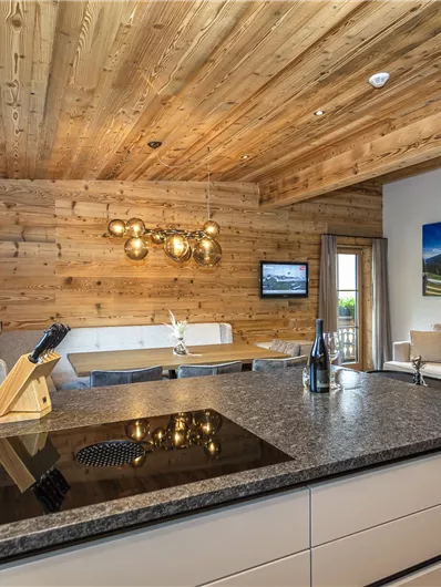 Een moderne keuken met een houten plafond en elegante meubels. De ruimte is licht en uitnodigend, met een gezellige woonkamer.