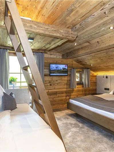 Een gezellige slaapkamer met houten plafond en modern interieur. Er is een tweepersoonsbed, een Eenpersoonsbed en een steile ladder naar de bovenste slaapruimte.