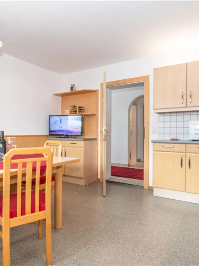 Een gezellige keuken met een eettafel en stoelen. De wanden zijn licht en er is een muur met een berglandschap.