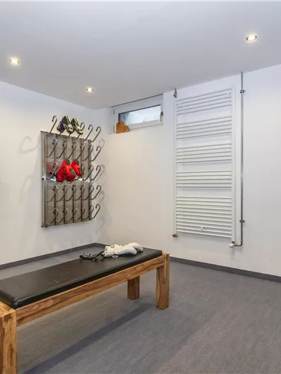 Een moderne ruimte met een houten bank en ski- en sportuitrusting aan de muur. De ruimte is goed verlicht en goed georganiseerd.