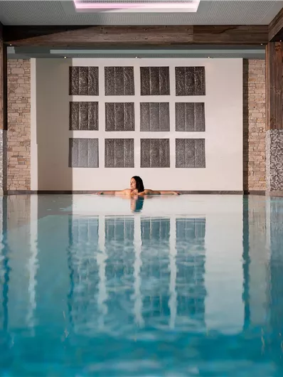An elegant pool area with clear water and a relaxing atmosphere. A person is sitting in the water and enjoying the tranquility.
