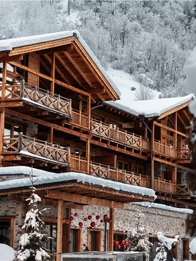 A charming mountain chalet in the snow with wooden balustrades. The surroundings are wintry and peaceful.
