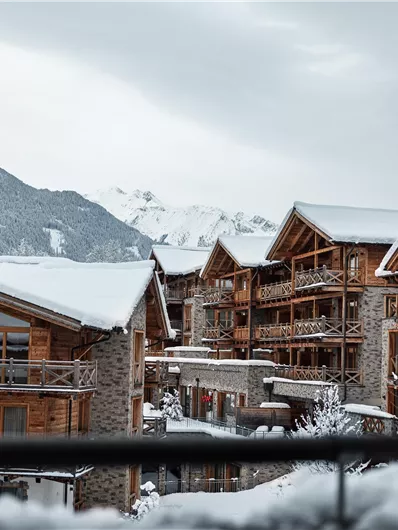 A picturesque winter landscape with chalets and snow-covered roofs. Majestic mountains can be seen in the background.