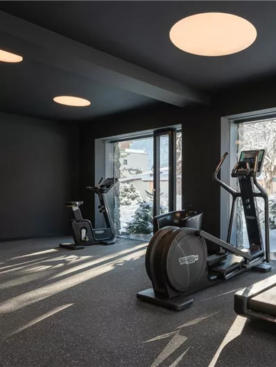 A modern gym with a view of the snow outside. There are treadmills and a fitness area with equipment.