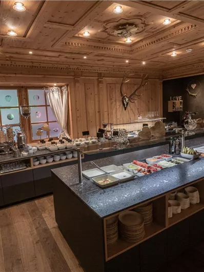 Ein stilvoller Essbereich mit Holzverkleidung und eleganten Tischen. Auf dem Buffet sind verschiedene Speisen und Getränke dekorativ angerichtet.