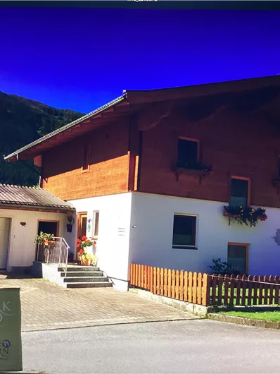 Ein gemütliches Haus mit Holzverkleidung und einem hellen Außenanstrich. Es liegt in einer ländlichen Umgebung mit einer schönen Aussicht auf die Berge.
