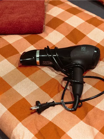 A hairdryer is lying on a checkered towel. Next to it is a red towel.