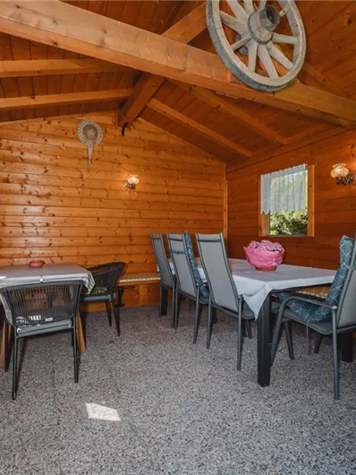 A cozy wooden room with a large table and chairs. There is a comfortable atmosphere with decorative elements on the walls.
