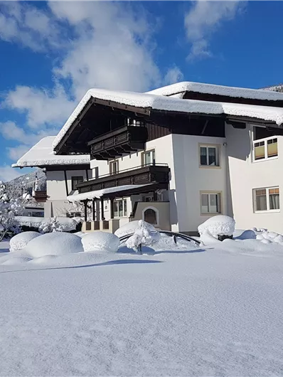 A beautiful house in the snow, surrounded by a winter landscape. The clear sky and the snow-covered trees create an idyllic atmosphere.