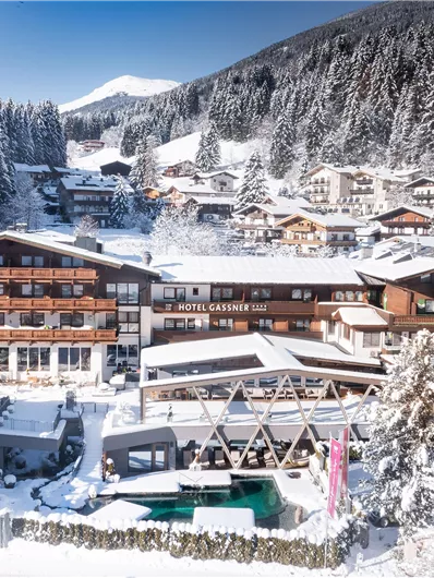 Een met sneeuw bedekt hotel in een idyllisch winterlandschap. Omgeven door bergen en bos biedt het een rustige sfeer.