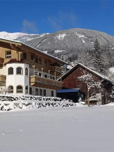 Een schilderachtig winterlandschap met sneeuwbedekte gebouwen en bomen. Op de achtergrond zijn de besneeuwde bergen te zien.