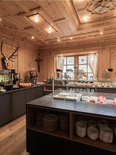 Een gezellige ruimte met houten wandbekleding en natuurlijk licht. Op het buffet zijn verschillende gerechten en drankjes voorbereid.