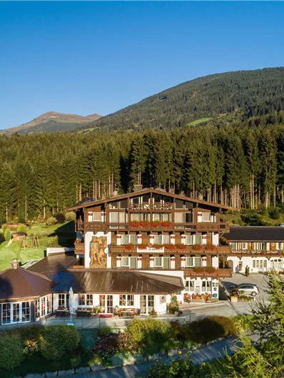 Ein malerisches Hotel, umgeben von dichten Wäldern und Bergen. Der klare Himmel schafft eine einladende und ruhige Atmosphäre.