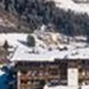 Een schilderachtig winterscenario met met sneeuw bedekte heuvels en een gezellig hotel. De heldere blauwe lucht maakt het idyllische beeld compleet.