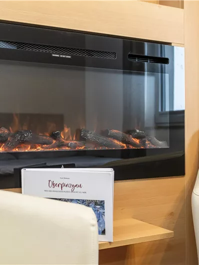 Een moderne elektrische haard in een gezellige kamer. Naast de haard staan twee comfortabele fauteuils.