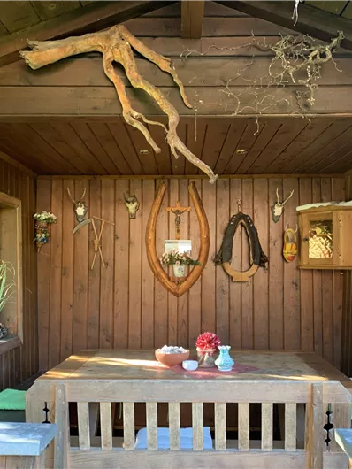A cozy room with wooden paneling and rustic decorations. 

Flowers and some accessories are on the table, while various hunting trophies hang on the walls.