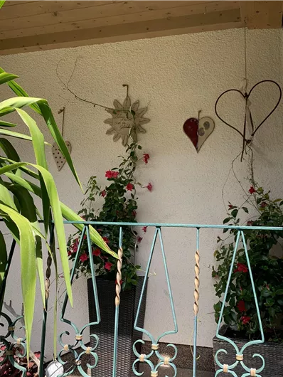 An inviting balcony with blooming plants and decorative elements. In the background, heart and sunflower hangers can be seen.