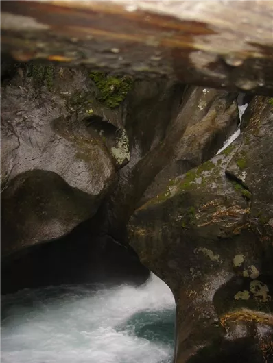 Een indrukwekkende rotsformatie met stromend water. De plek is omgeven door natuur en straalt rust uit.