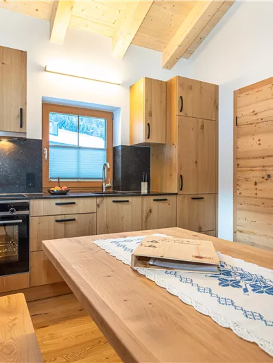 Een moderne keuken van hout met een eetgedeelte. Op de tafel staan een fles wijn en twee glazen.