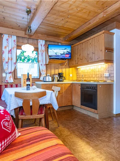 Een gezellige vakantiewoning met houten interieur en een eetgedeelte. De keuken is modern uitgerust en er is een televisie zichtbaar.