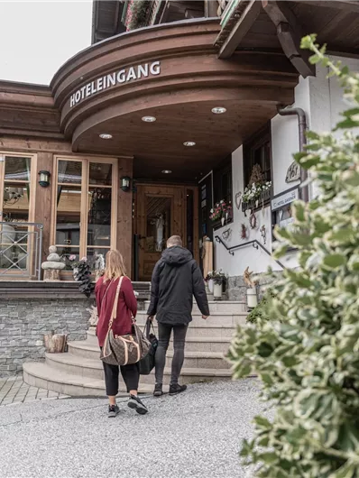 Ein gemütliches Restaurant mit Holzfassade und einladendem Eingang. Zwei Personen nähern sich den Stufen vor dem Eingang.