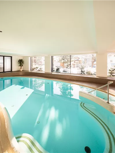A modern indoor pool in a cozy room. Large windows offer a view of the winter landscape outside.