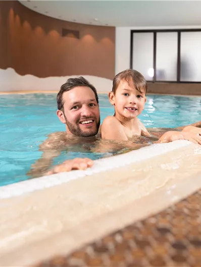 Een vader en zijn zoon genieten samen van het water in het zwembad. De omgeving is helder en uitnodigend.