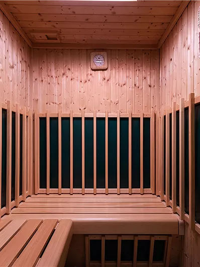 Eine moderne Sauna mit Holzverkleidung und Bänken. Die Wände sind überwiegend aus Holz und bieten eine entspannende Atmosphäre.