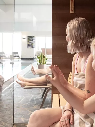 Eine entspannte Familie im Wellnessbereich. Im Hintergrund sieht man einen Pool und Sonnenliegen.