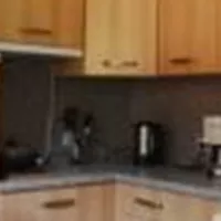 Eine gemütliche Küche mit holzfarbenen Schränken und modernen Geräten. Der Tisch ist gedeckt und hat Geschirr in verschiedenen Farben.