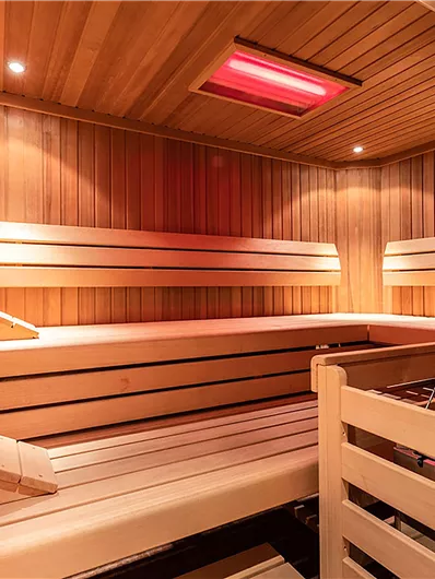 Eine moderne Sauna mit Holzverkleidung und warmem Licht. Die Bänke sind zum Entspannen und Erholen eingerichtet.