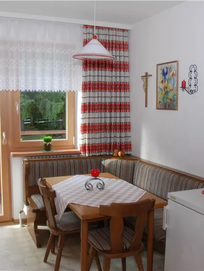 Eine gemütliche Küche mit einem Essbereich und einem großen Fenster. Der Raum ist in warmen Farben dekoriert und hat einen Blick auf die Natur.