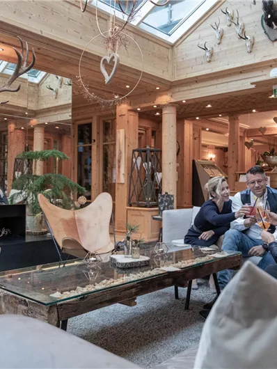 Eine gemütliche Lounge mit Holzdekor und stilvollen Möbeln. Menschen sitzen zusammen und genießen Getränke in einer warmen, einladenden Atmosphäre.