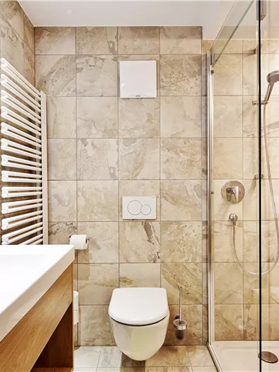 Ein modernes Badezimmer mit eleganter Fliesenwand und einer Dusche aus Glas. Das Waschbecken ist stilvoll integriert und es gibt einen Handtuchheizkörper.