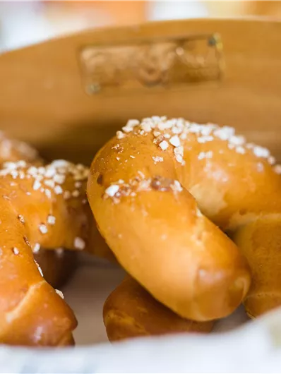 Frische Brötchen in einem Korb, auf einem weißen Tuch. Die Brötchen sind goldbraun und einladend.