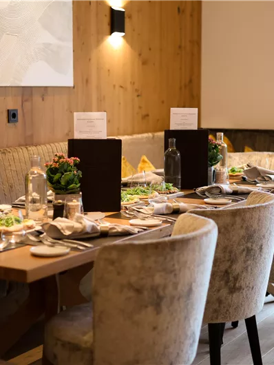 Ein elegantes Restaurant mit einer gedeckten Tafel. Die gemütlichen Stühle und die warmen Holzwände schaffen eine einladende Atmosphäre.