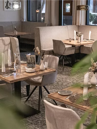 Ein modernes Restaurant mit eleganten Tischen und Stühlen. Die Atmosphäre ist gemütlich und einladend, perfekt für eine entspannte Mahlzeit.