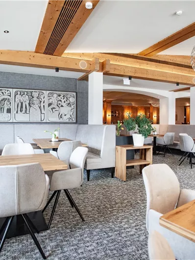 Ein modernes Restaurant mit hellen Farben und stilvollen Möbeln. Die Wände sind mit Kunstwerken dekoriert, und frische Blumen schmücken die Tische.