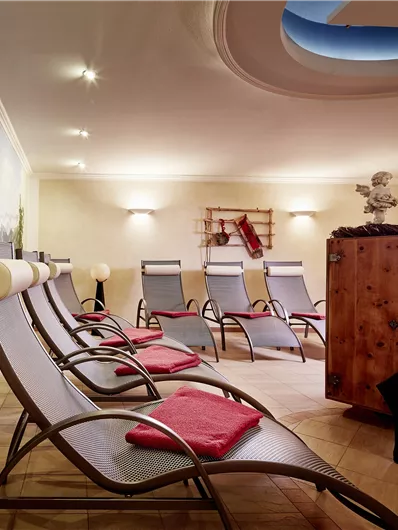 Een ontspannende wellnessruimte met ligstoelen en een rustgevende wanddecoratie. De ruimte straalt rust en comfort uit.