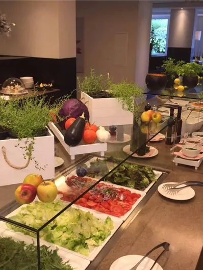 Een kleurrijk saladeschotel met verse groenten en fruit. Op de tafel staan verschillende kommen met salade en dips.