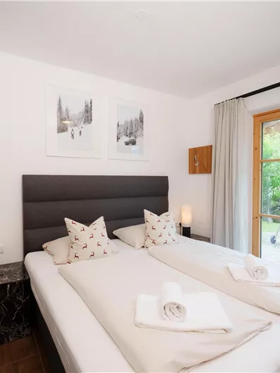 Ein modernes Schlafzimmer mit zwei Betten und eleganter Einrichtung. Große Fenster bieten Blick ins Freie.