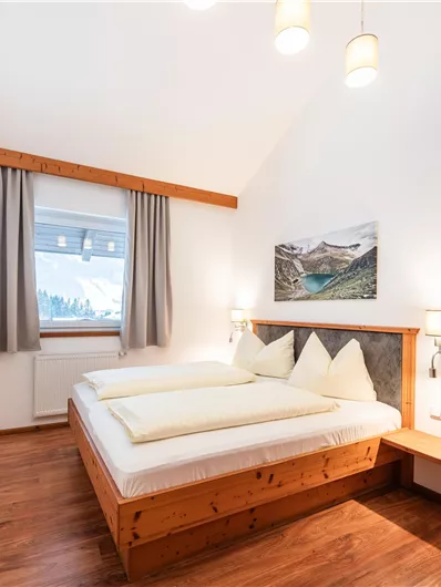 Ein gemütliches Zimmer mit einem Doppelbett und Holzverkleidung. Das Fenster bietet einen Blick auf die Landschaft.