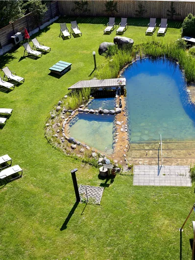 Een verzorgde tuin met een klein vijver en ligstoelen om te ontspannen. De vijver is omgeven door groene vegetatie, ideaal voor een gezellige dag in de buitenlucht.