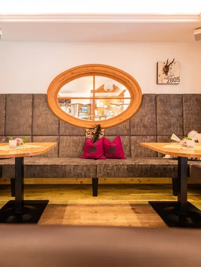 Een stijlvol restaurant met comfortabele banken en een rond raam. De inrichting is modern en uitnodigend, ideaal voor gezellige bijeenkomsten.