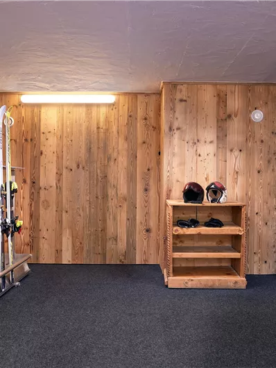 Een skiruimte met houten bekleding. Skis, helmen en uitrusting zijn netjes opgeborgen.